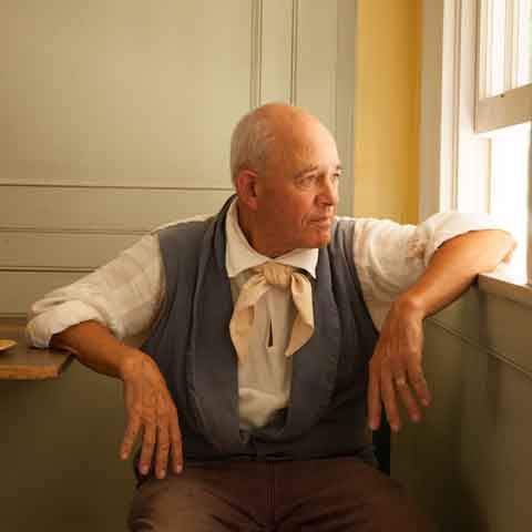 man dressed in a historical outfit looking out the window